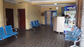 A hotel reception area with blue chairs, a reception desk, and a sign for 'KEBLAT SUITES'. - Keblat Hotel  Suites (Abeokuta)