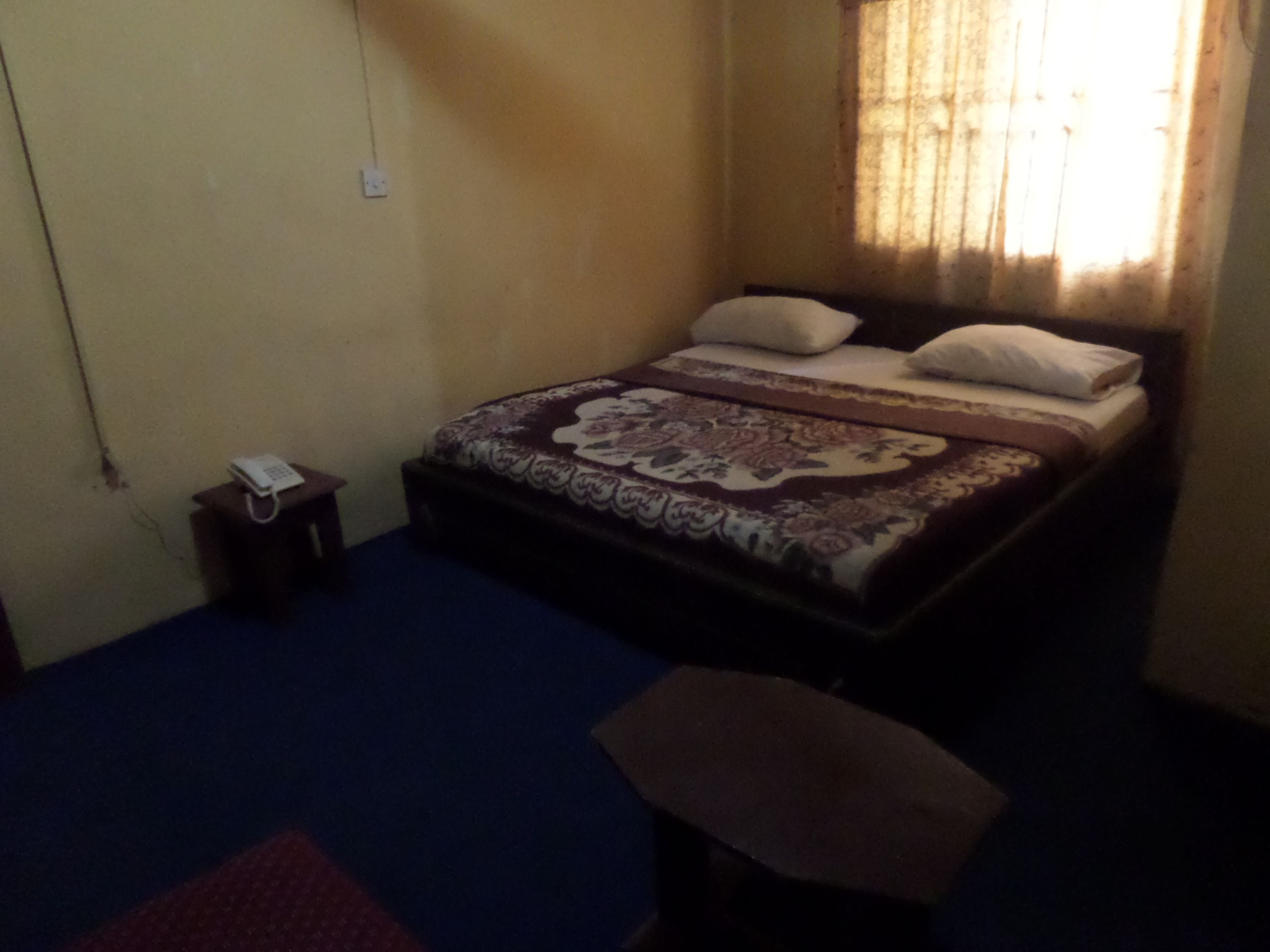 A bedroom with a bed, a bedside table, and a telephone.
