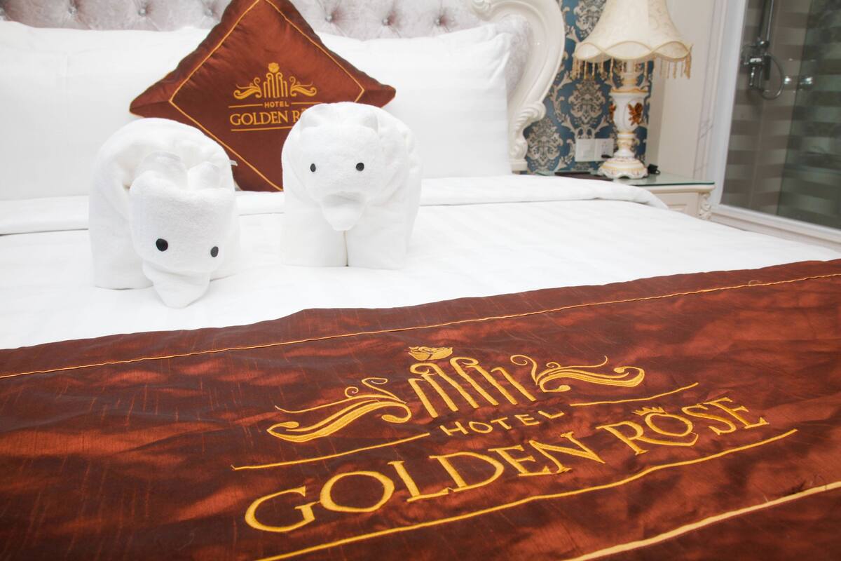 Una cama de hotel con un edredón marrón que muestra el nombre y el logo del hotel.