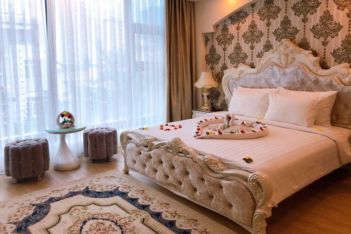Un dormitorio elegante con una cama grande, cabecero decorado y una alfombra ornamental.