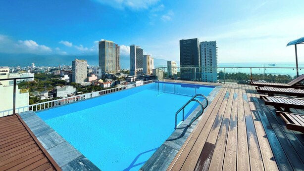 A rooftop pool with a view of a cityscape and the ocean.