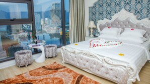 A bedroom with a large bed, a view of the city, and a cityscape visible through the window.