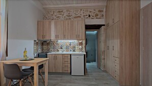 Une cuisine compacte avec des meubles en bois, un pare-feu en carreaux et un petit réfrigérateur.