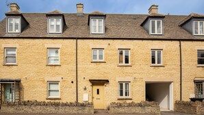 Un bâtiment en pierre à deux étages, doté de nombreuses fenêtres, d’une porte centrale et d’un mur en pierre à sa base.