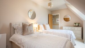 Une chambre avec deux lits, une commode, un miroir et un luminaire au plafond.
