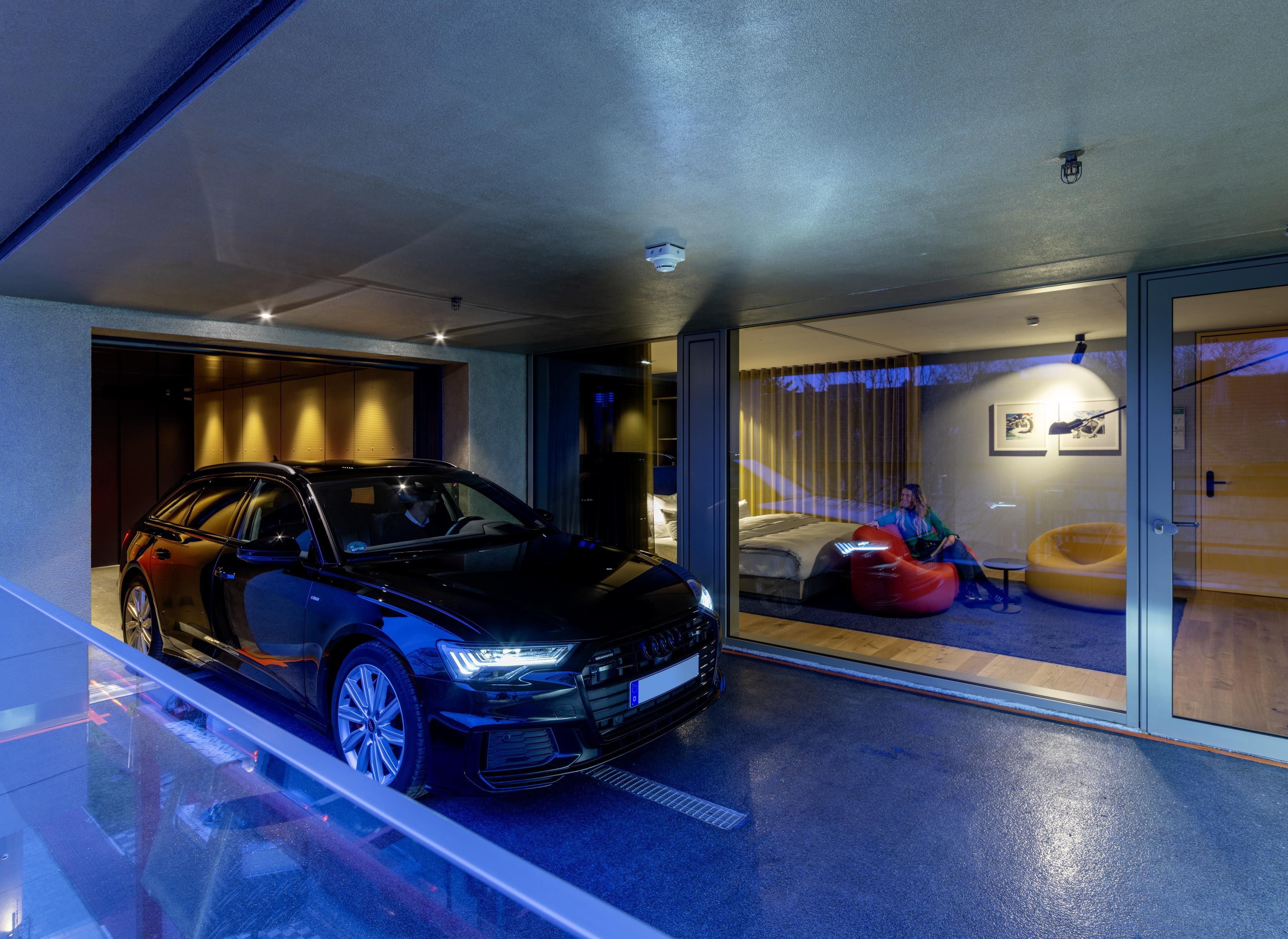 A modern interior with a car parked outside, a bed, and a red bean bag chair.