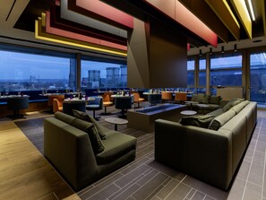 Een moderne lounge met banken, tafels en uitzicht over de stad.