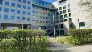 Un bâtiment moderne à plusieurs étages, doté de grandes fenêtres et d’un espace d’entrée abrité.