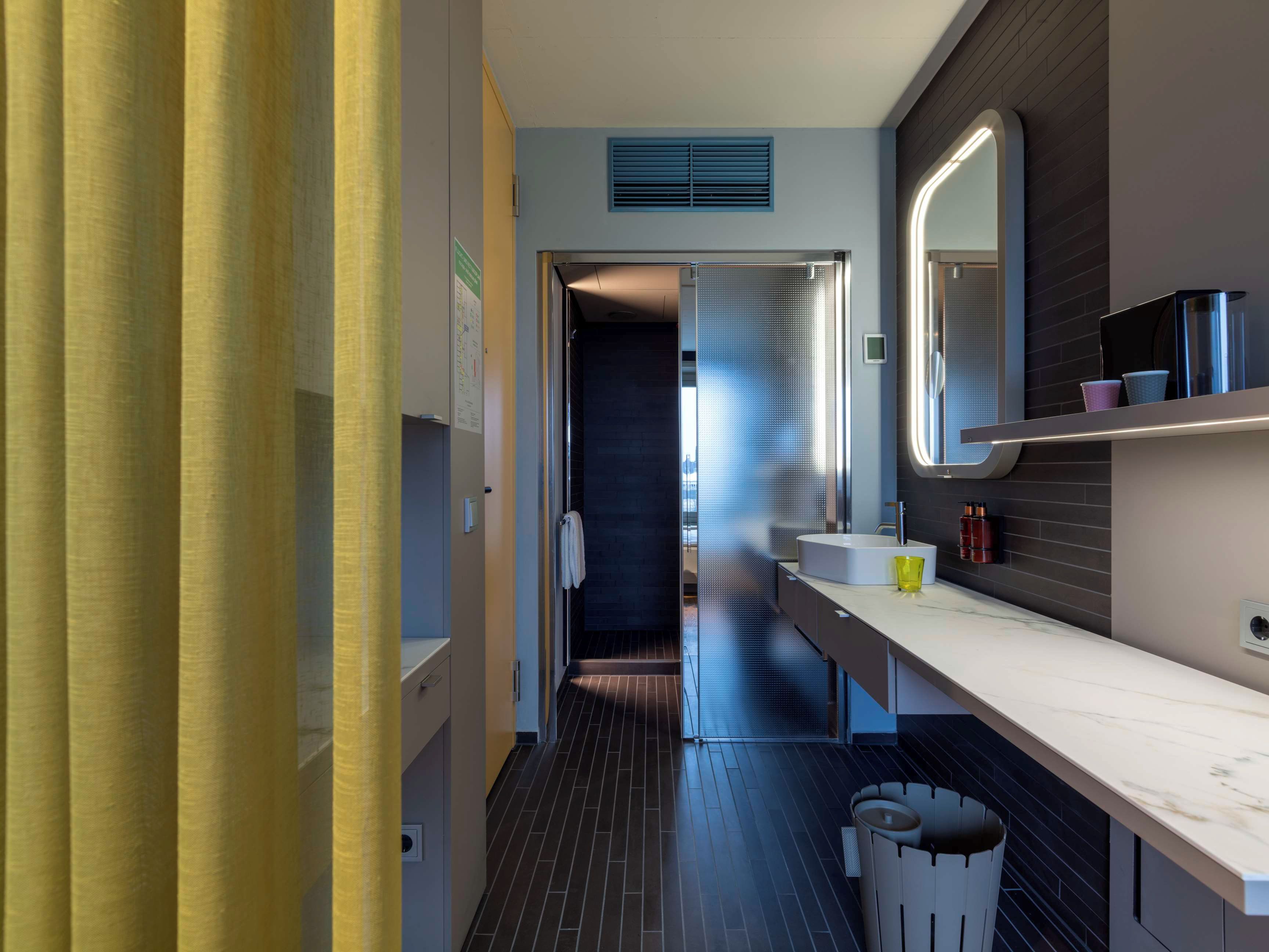 A modern bathroom with a large mirror, a sink, and a toilet.