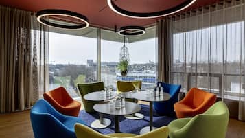 Una sala de reuniones moderna con una mesa redonda, sillas coloridas y ventanas amplias con vistas a la ciudad.