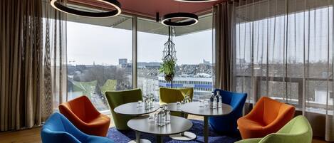 Una sala de reuniones moderna con una mesa redonda, sillas coloridas y ventanas amplias con vistas a la ciudad.