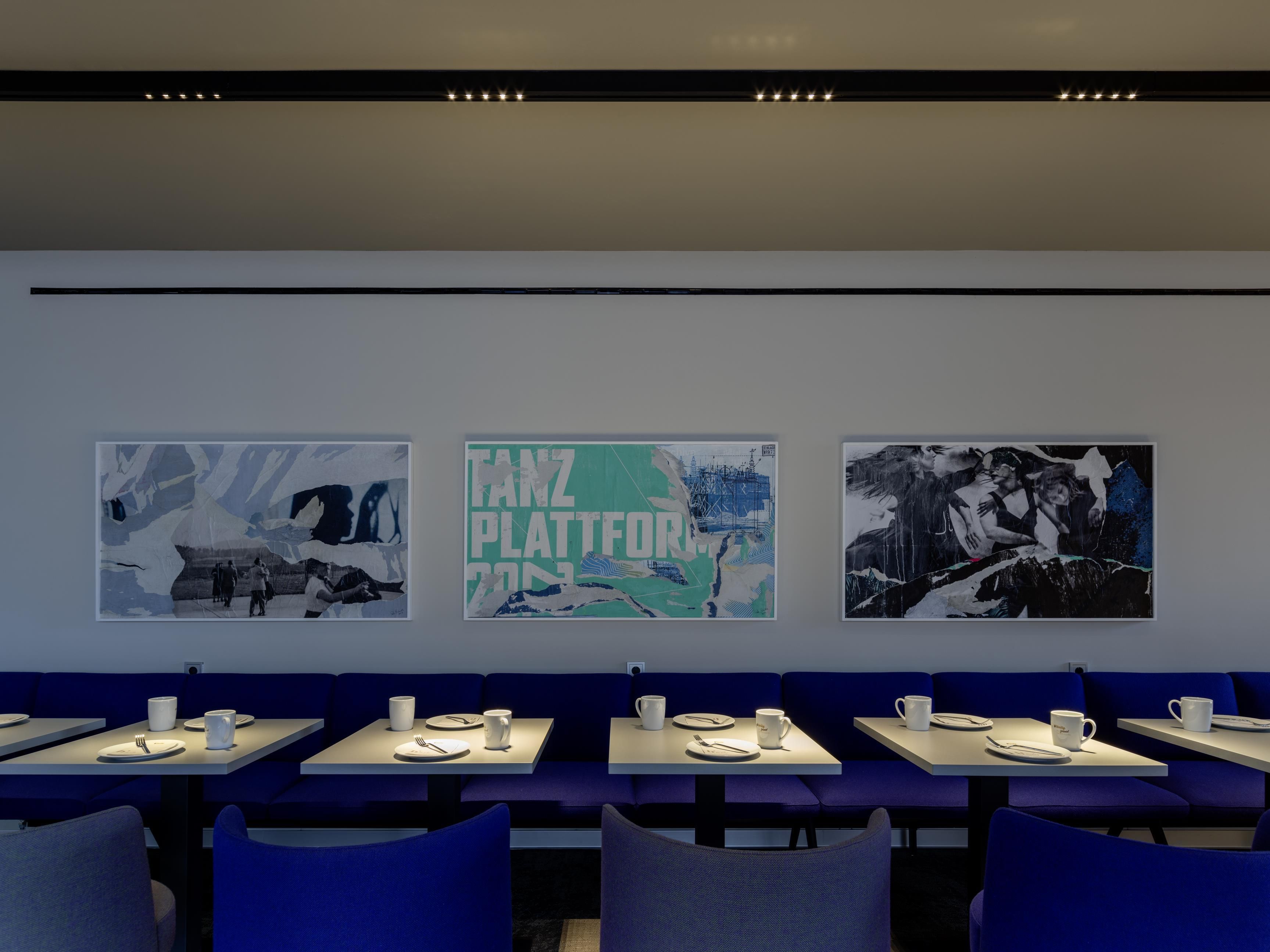 A restaurant with tables and chairs, and three artworks on the wall.