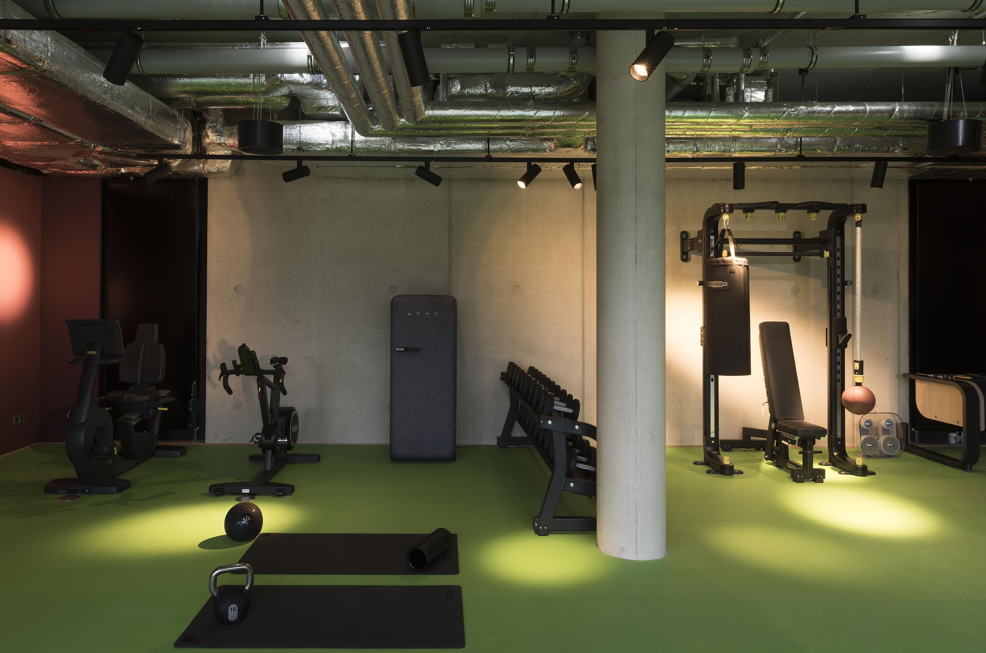 Una palestra con attrezzature per esercizi, un pavimento verde e una colonna bianca.