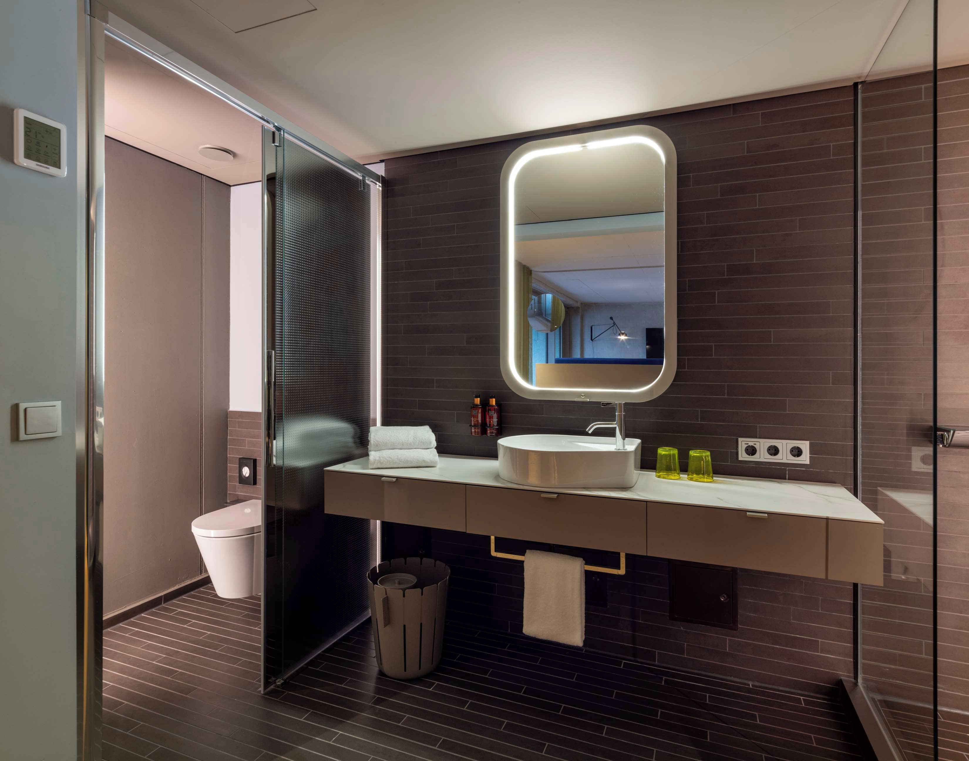 A modern bathroom with a large mirror, a sink, and a toilet.