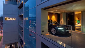 A modern building with a glass facade, a car displayed in the window, and the sign 'b'mine'.