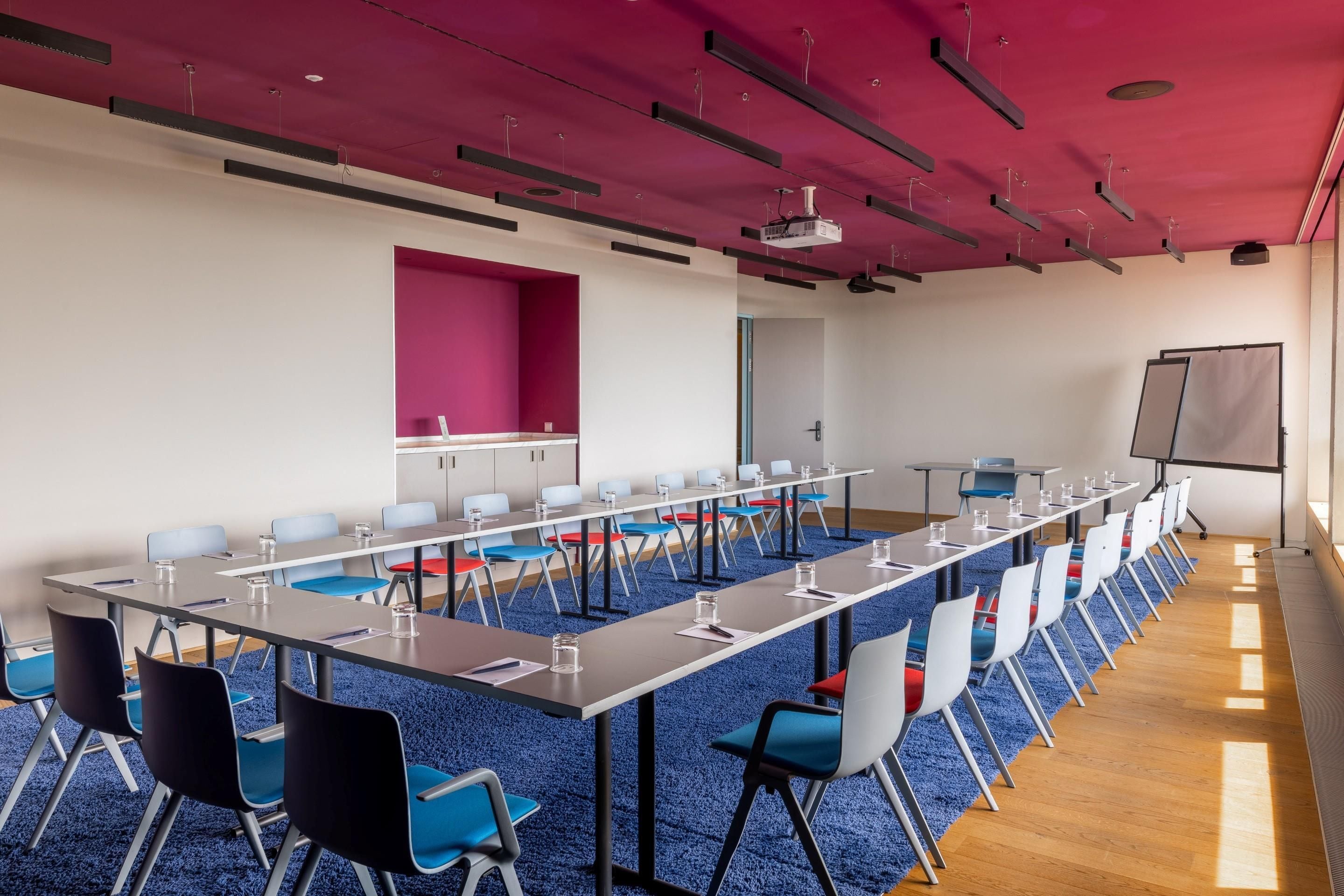 A conference room with a long table, chairs, a projector, and a whiteboard.