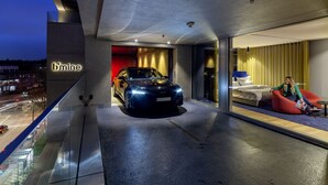Een modern hotel met een auto voor de deur, een balkon en uitzicht op de stad.