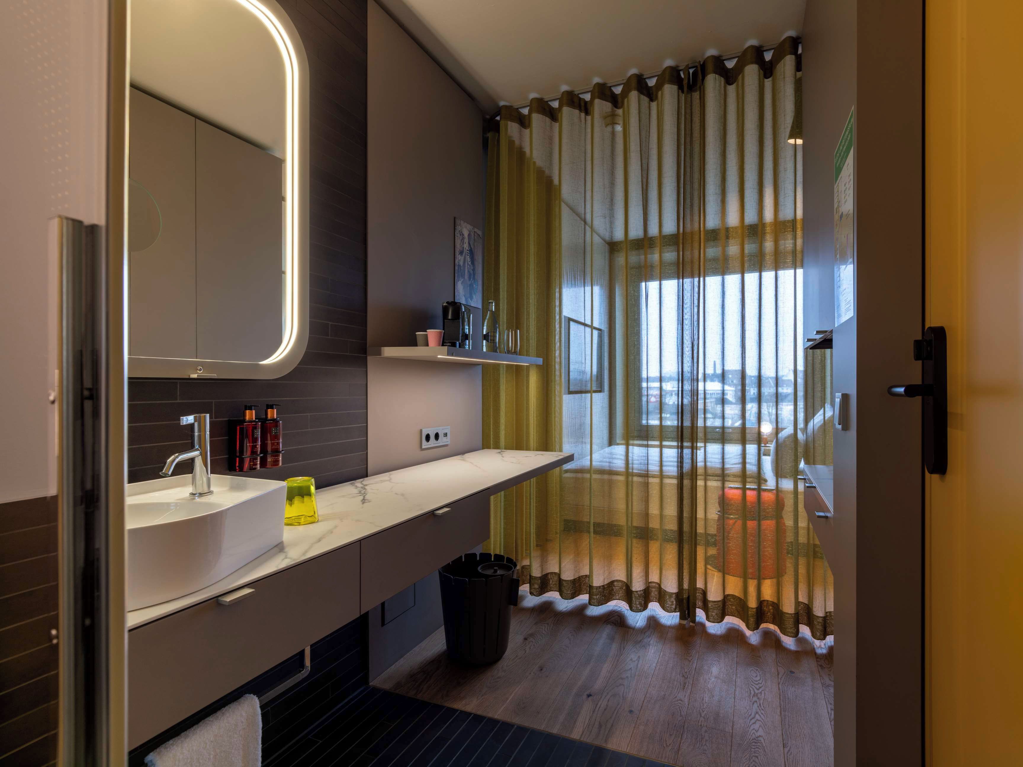 A modern bathroom with a large mirror, a sink, and a shower area.