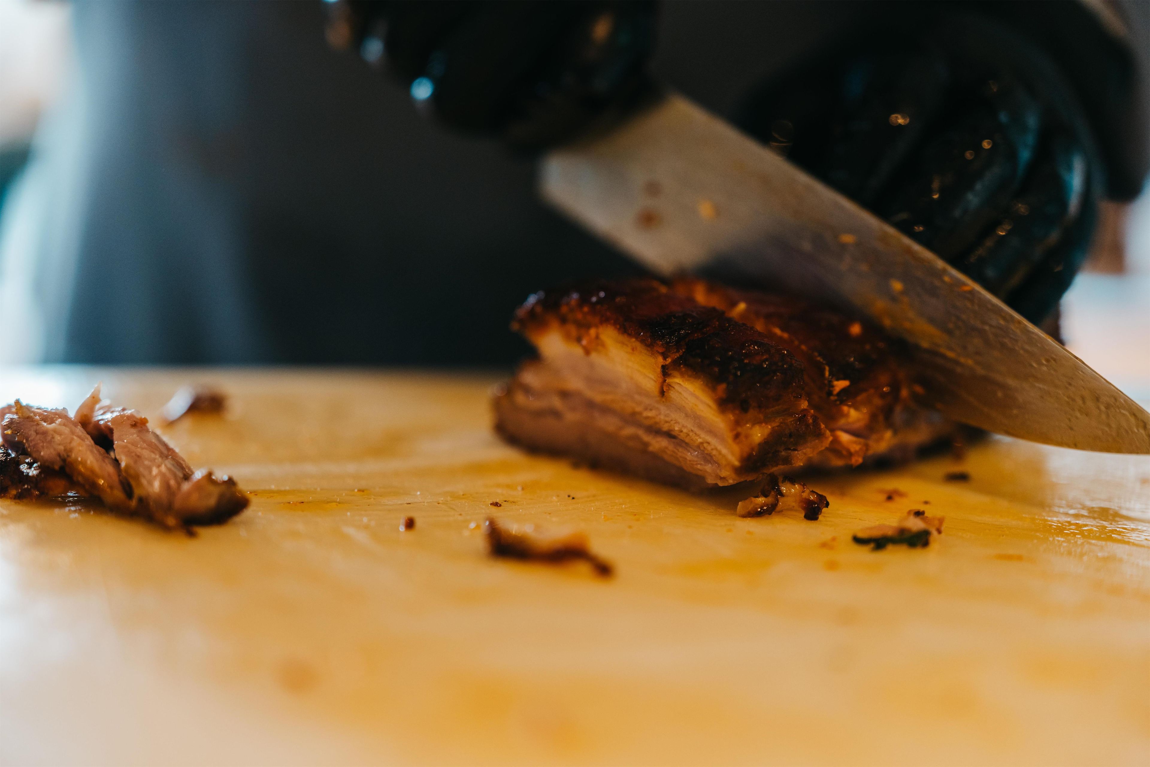 A close-up of a person slicing meat on a cutting board.