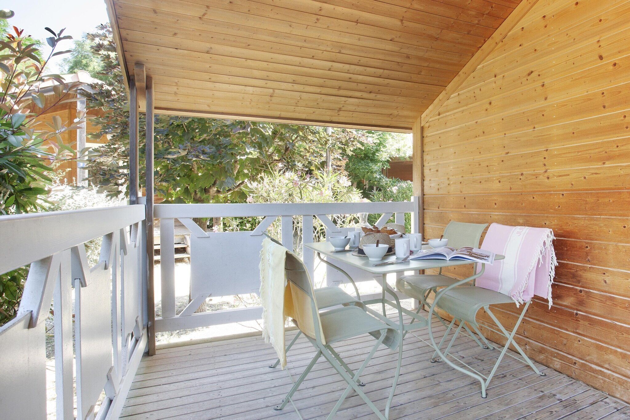 A covered outdoor seating area with a table, chairs, and a bench.
