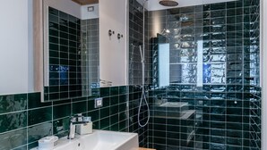 Un baño moderno con tocador de madera, un espejo grande y cabina de ducha con puertas de vidrio.