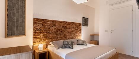 Une chambre à coucher moderne avec une tête de lit en bois, un lit avec une literie blanche et une table de chevet avec une lampe.