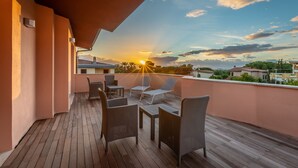 Terraza de madera con mobiliario de mimbre, con vistas a la puesta de sol.