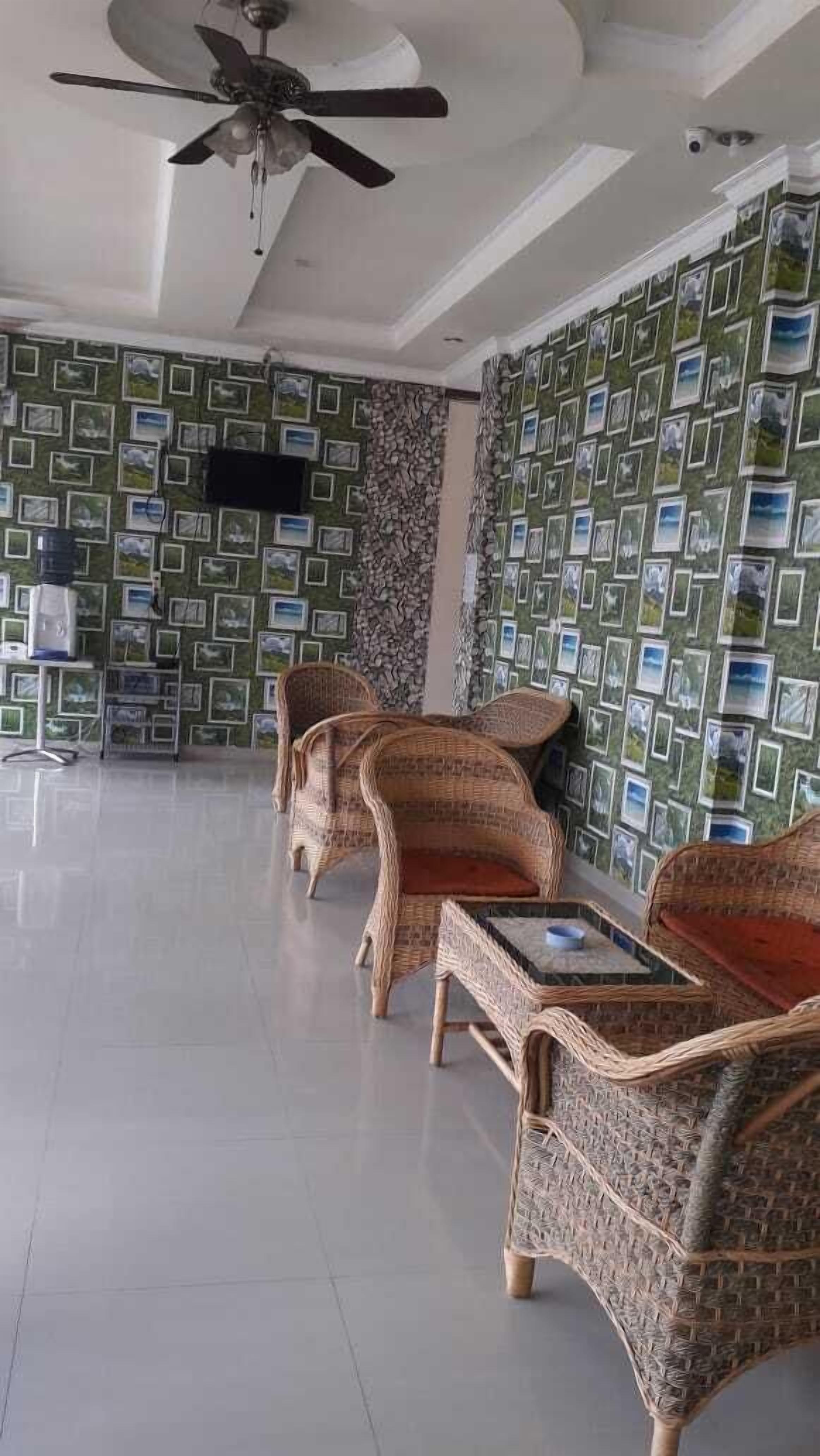 A spacious room with a ceiling fan, wicker furniture, and patterned wallpaper.