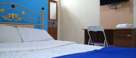 A bedroom with a bed, a television mounted on the wall, a chair, and a wooden dresser.