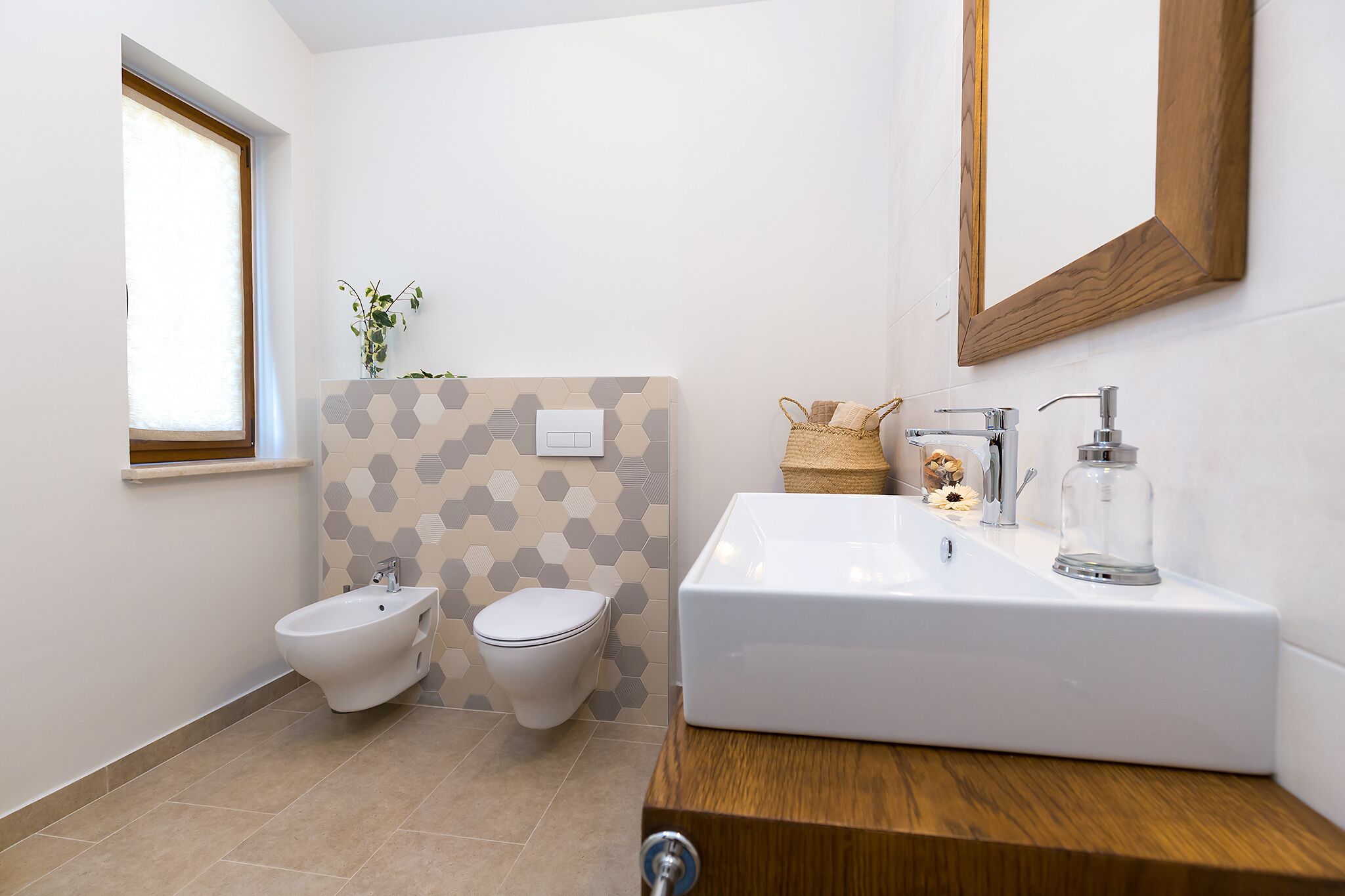 A modern bathroom with a bidet, toilet, and a large sink with a mirror above.