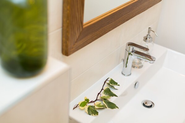 Une salle de bain avec un lavabo blanc, un robinet chromé et un miroir encadré en bois.