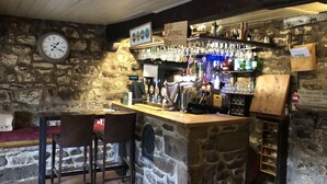 Un'area bar con pareti in pietra, una sveglia e diversi bicchieri e bottiglie.