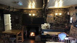 Un pub accogliente con interni in pietra, un camino, mobili in legno e un bersaglio per freccette.