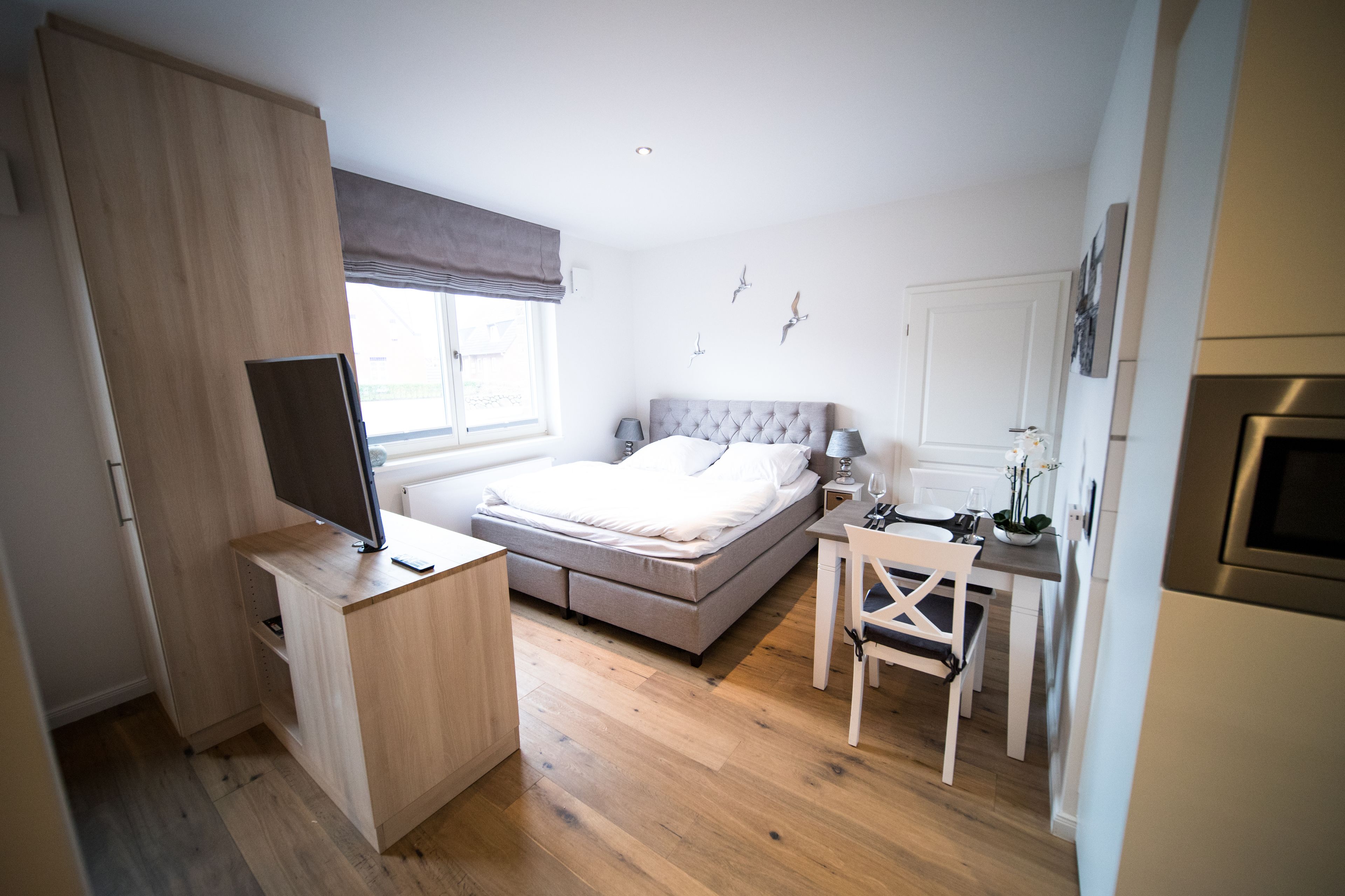 Een slaapkamer met een bed, een bureau, een stoel, een televisie en een raam.