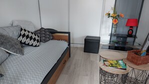 A modern bedroom with a bed, bedside tables, a small stool, and a red lamp. - Quiet home in the 2-star Mimosa City (Mandelieu-la-Napoule)
