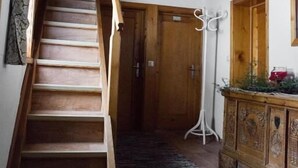 Una escalera de madera que lleva a una puerta, un armario de madera con un espejo y una lámpara de pie.