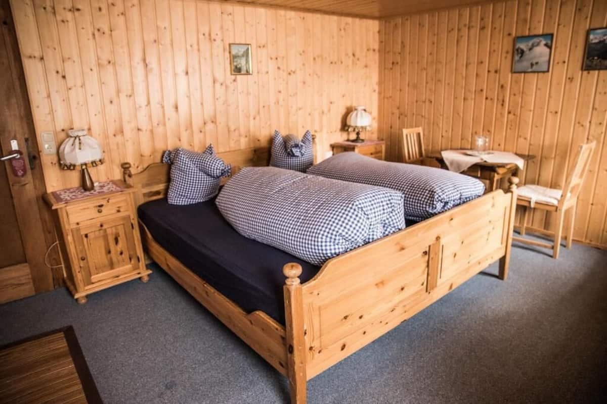 Une pièce aux murs lambrés, comprenant deux lits, un bureau et une chaise.