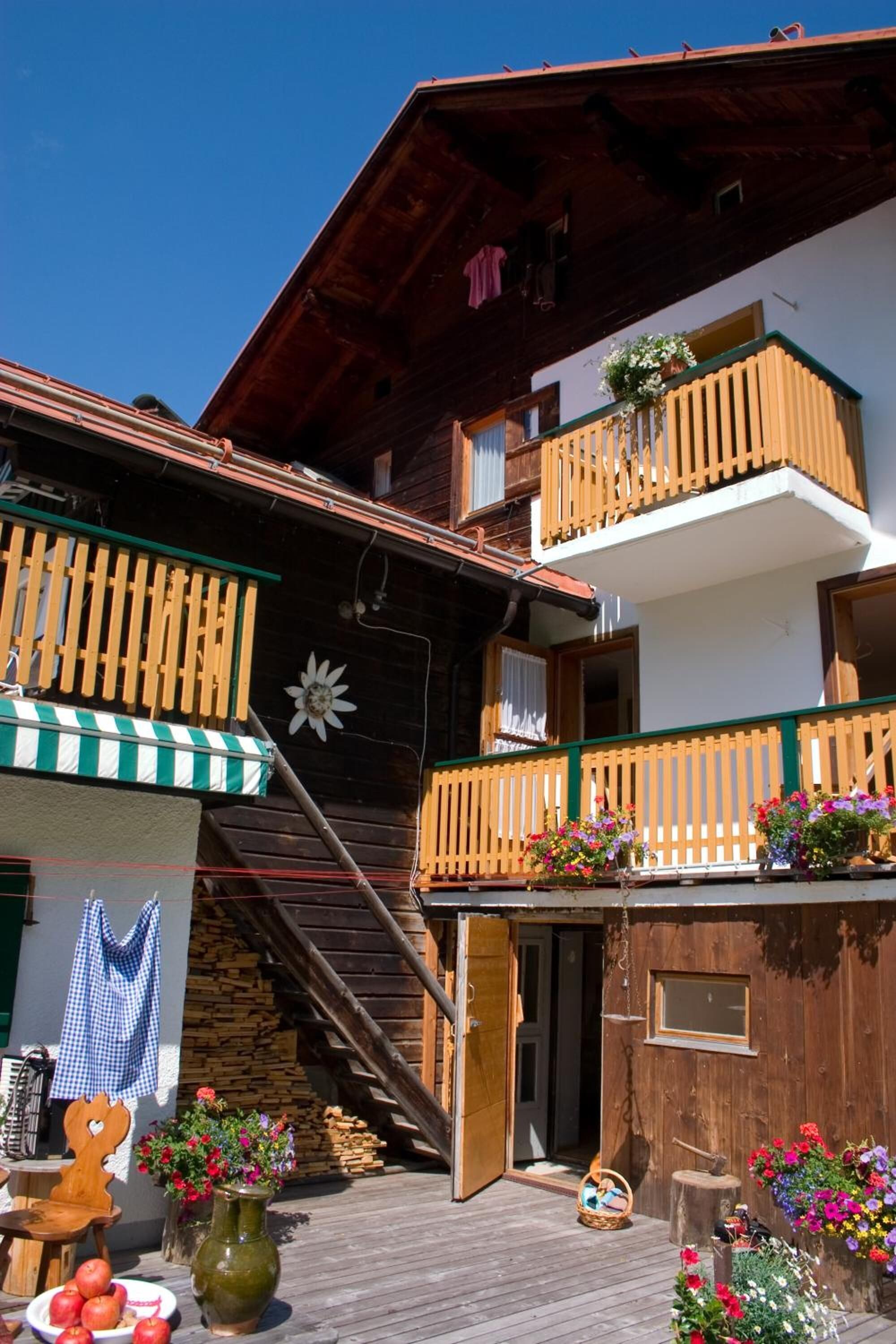 Una cabaña de madera con balcones, una terraza de madera y asientos exteriores.