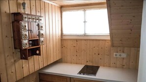 Una pequeña cocina con paredes de madera, un ventanal y un mueble empotrado con azulejos decorativos.