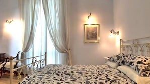 Une chambre à coucher avec un lit, des tables de chevet, un bureau et des rideaux.