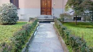 Un bâtiment doté d’une grande porte en bois, d’un chemin en pierre et de haies bien entretenues.