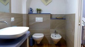 Une petite salle de bain avec un lavabo blanc, des toilettes et un bidet.