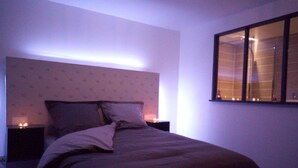 A bedroom with a bed, two bedside tables, and a window with curtains.