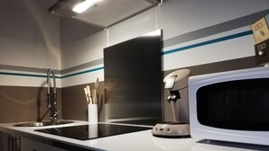 A modern kitchen with a stainless steel sink, a white microwave, and a coffee machine.