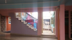 Una escalera con barandales metálicos que lleva a una plataforma, un piso de baldosas y una puerta que da a un espacio exterior.
