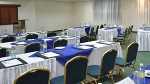 Un salón de conferencias con varias mesas, sillas y botellas de agua.