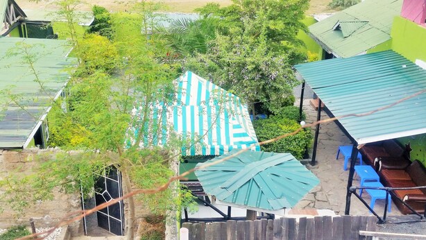 Un barrio residencial con una casa que tiene un toldo a rayas, una valla de madera y un pequeño jardín.