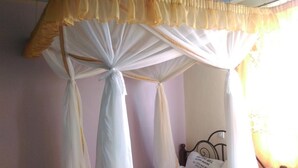 Una cama con cabecera, un cartel en la pared y una ventana con cortinas.