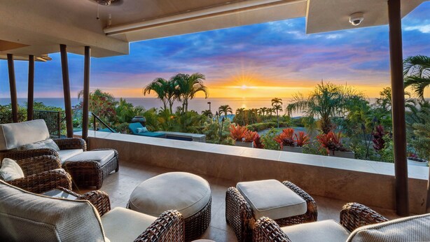 A balcony with wicker furniture and a view of the sunset over the ocean. - 🏖️Ocean View Kona Home | Saltwater Pool + Private Suites (Kailua Kona)