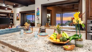 A spacious kitchen with a large island, granite countertops, and a view of the sunset. - 🏖️Ocean View Kona Home | Saltwater Pool + Private Suites (Kailua Kona)